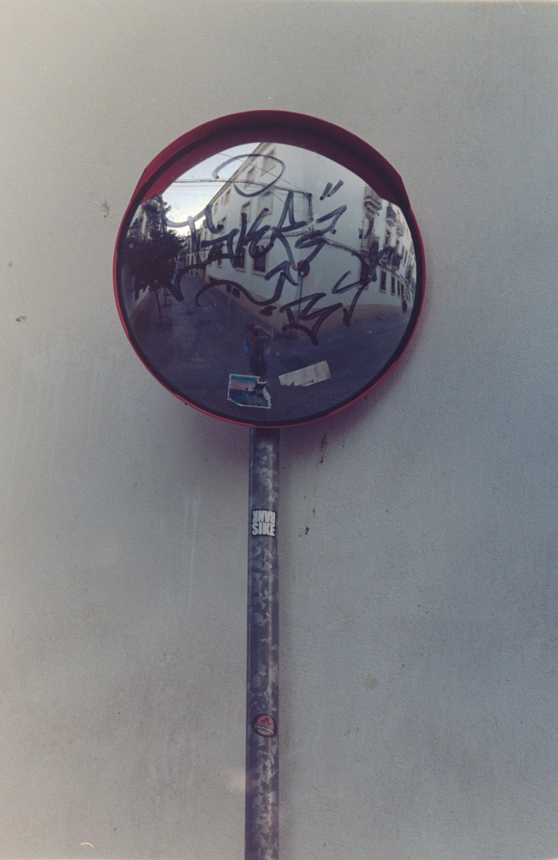 A mirror on a post in the street, with me taking the photo in the reflection.