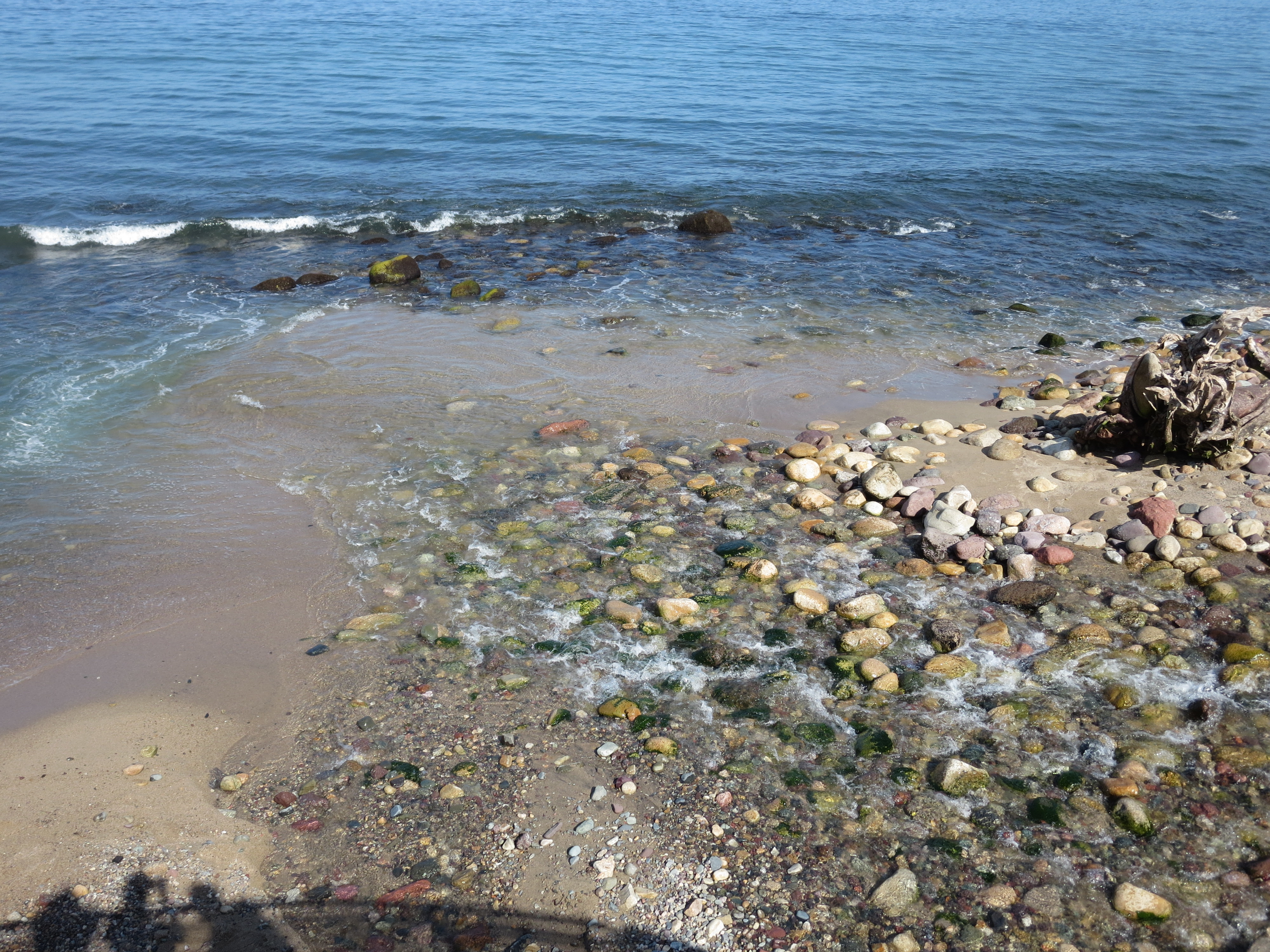 Picture of beach coastline close-up. Rocks on the sand and waves crashing towards the camera.